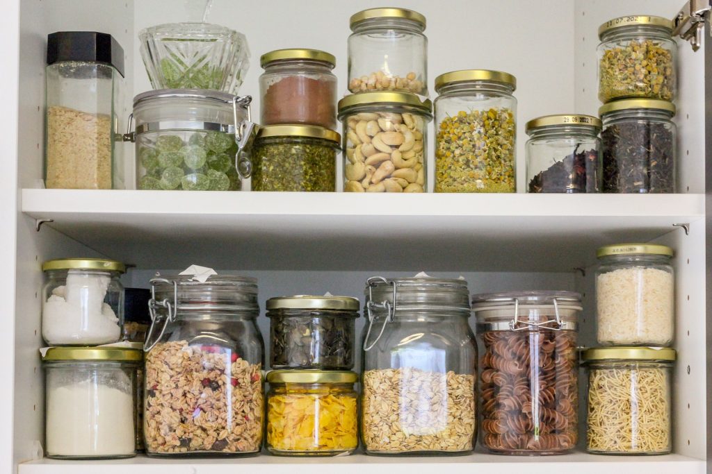 Two shelves show a variety of dried goods stored in clear jars.