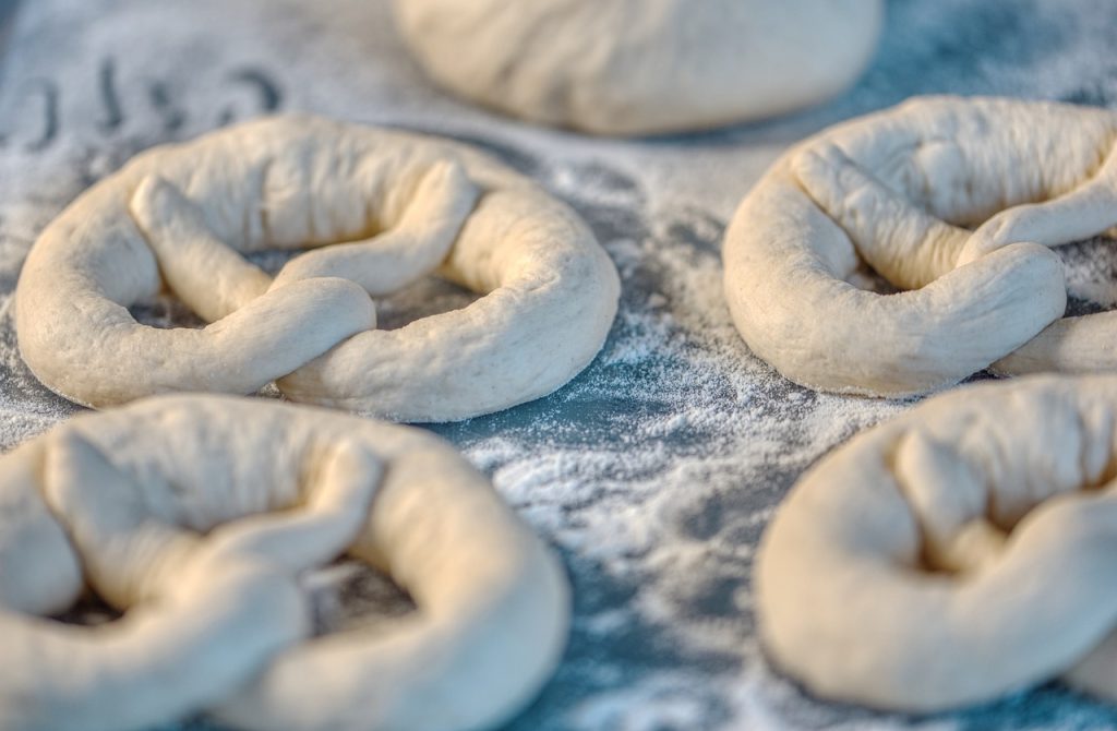 Raw dough shaped as pretzels sits on a floured surface.